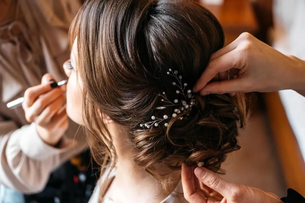 Ein Friseur und ein Visagist bereiten eine Braut auf den Hochzeitstag vor